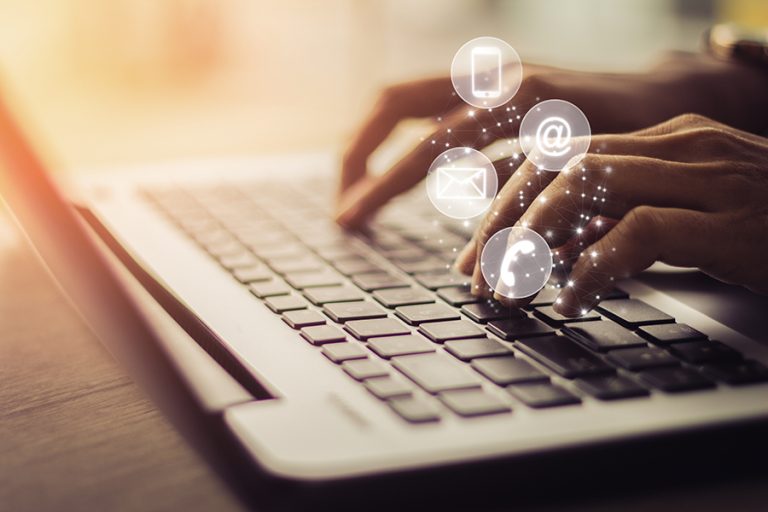 Person typing at laptop with icons for email and phone calls floating up from the keyboard.